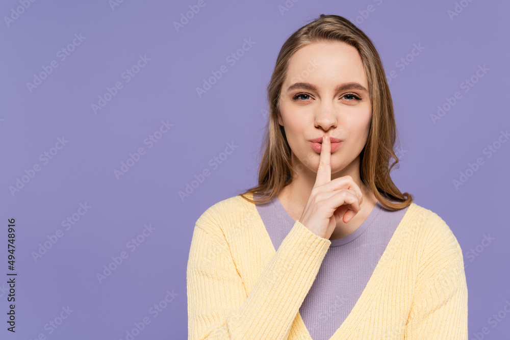 young woman looking at camera and showing hush sign isolated on purple. young woman looking at camera and showing hush sign isolated on purple.