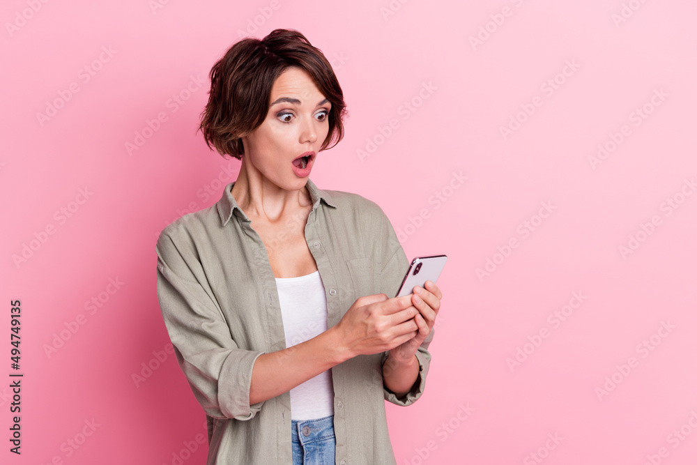 Photo of impressed pretty lady open mouth stare phone unexpected wear green shirt isolated on pink color background Photo of impressed pretty lady open mouth stare phone unexpected wear green shirt isolated on pink color background