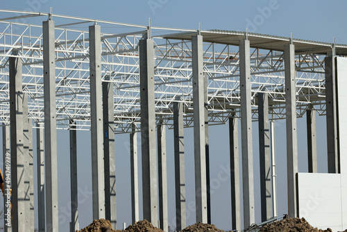 Biała stalowa konstrukcja hali magazynowej w czasie budowy.