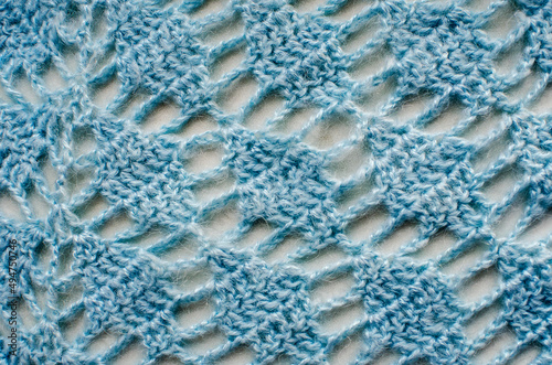 Openwork knitted fabric, abstract blue background. The concept of knitting, hobby, background for design.