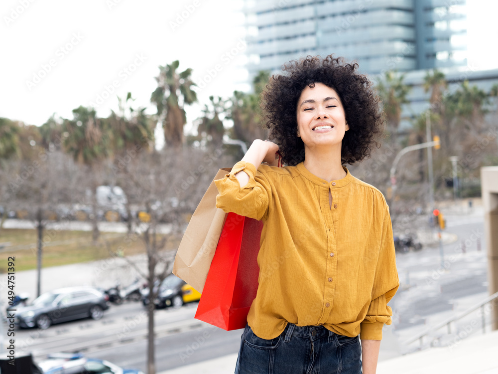 Fototapeta premium Smiling young african american woman with shopping bags