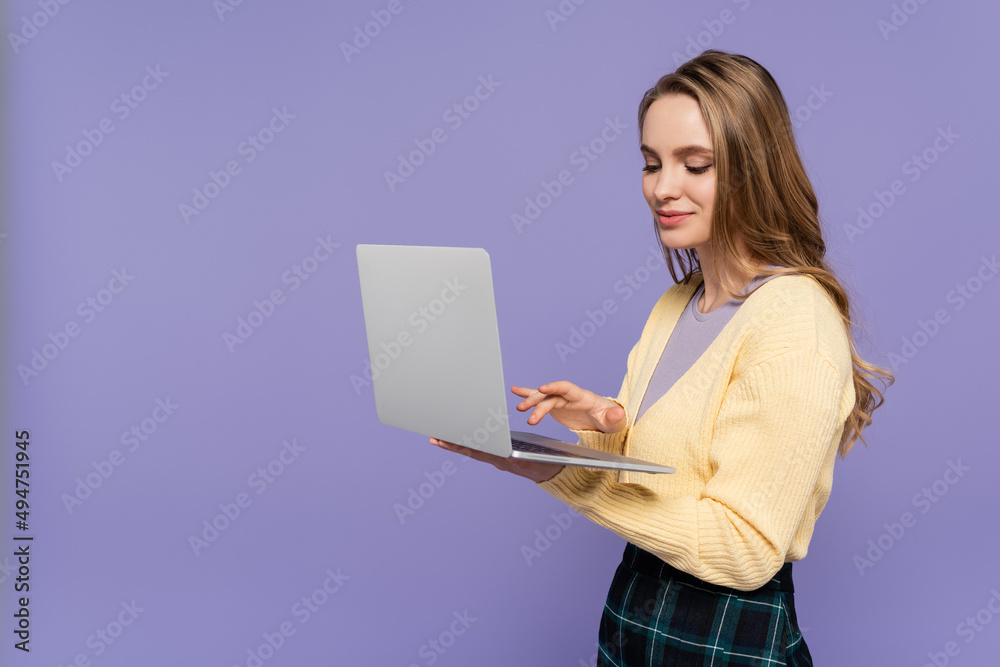 cheerful student using laptop isolated on purple. cheerful student using laptop isolated on purple.