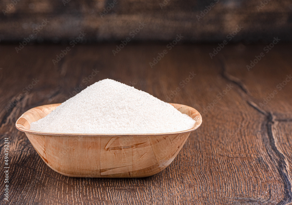 Wooden bowl full of sugar on a wooden background. Wooden bowl full of sugar on a wooden background.