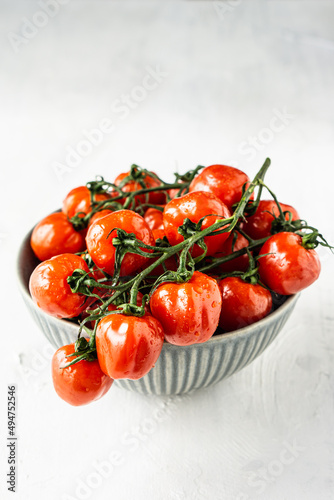 Small red cherry tomatoes in gray bowl on gray background