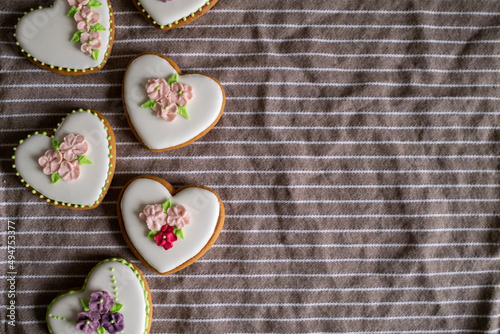 Fototapeta Naklejka Na Ścianę i Meble -  White gingerbread cookies with icing and flower decoration on a striped towel. Background for International Women's Day or Valentine's Day. High quality photo