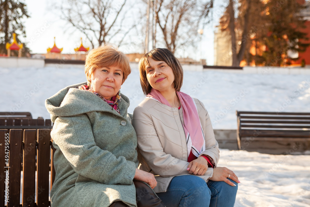 Fototapeta premium Portrait of two mature women sitting on bench in spring