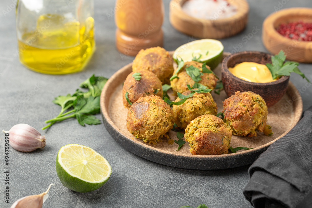Chickpea falafel with lime and sauce on a plate and grey table Chickpea falafel with lime and sauce on a plate and grey table