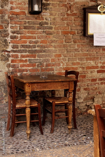 A wooden table and two chairs against the background of an old brick wall, Italy