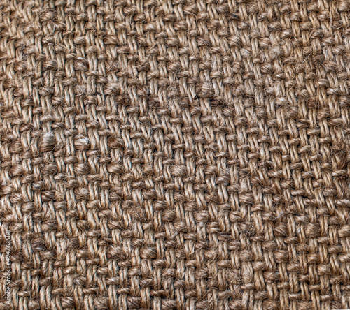 Textile burlap background. Close-up photo of burlap. The texture of the fibers and threads of the coarse fabric. Textile abstraction. Textile brown background. Sack texture background