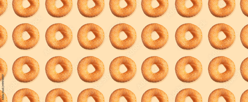 Creative food, baking pattern. Fresh round wheat bagel with sesame seeds on beige background. Crispy bread, healthy organic food, traditional pastries, bakery product. Breakfast bagel, long banner Creative food, baking pattern. Fresh round wheat bagel with sesame seeds on beige background. Crispy bread, healthy organic food, traditional pastries, bakery product. Breakfast bagel, long banner