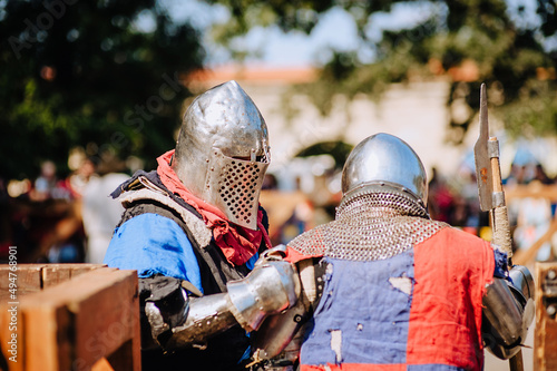 Two strong knights, warriors stand on the battlefield after defeating a rival, in armor with an ax in hand in the Middle Ages.