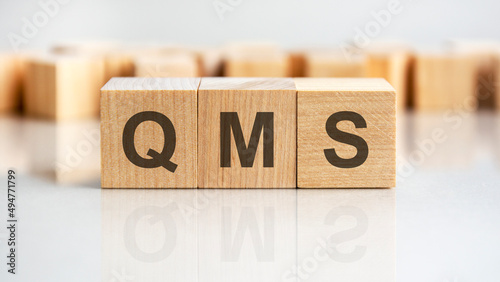 QMS - letters on wooden cubes. business as usual concept image. front view photo