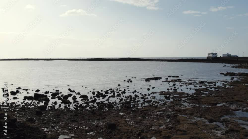 Volcanic formations and Atlantic Ocean view of Lanzarote Island. Rocky coast, black volcanic stones on the beach of Arrecife town. Canary Islands. Spain