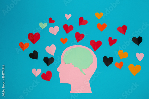 Fototapeta Naklejka Na Ścianę i Meble -  pink paper head and blue brain in it, around many colorful hearts, man in love and love of the air, head as copy space, flat design, human composition in love