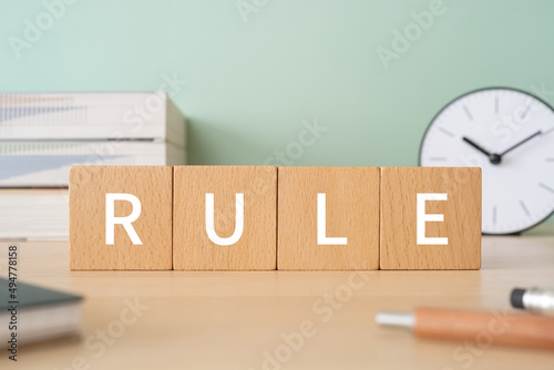 「RULE」と書かれた積み木、ペン、ノート、本、置き時計 photo