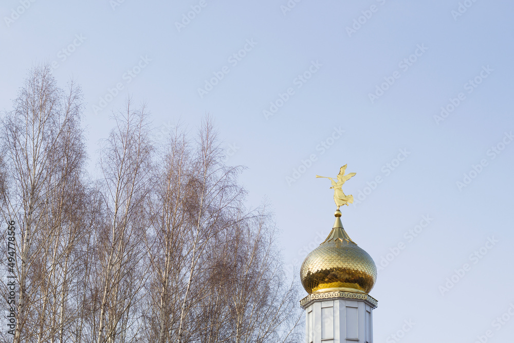 golden domes of orthodox church with blue sky and trees in early spring