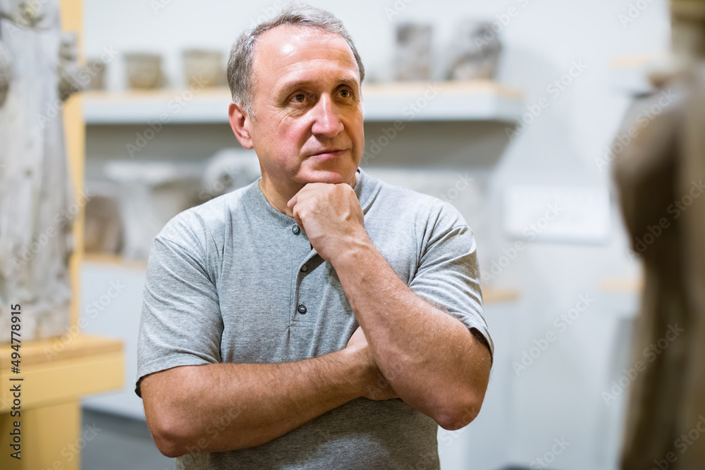 Naklejka premium middle aged man examining exposition in museum hall of ancient sculpture