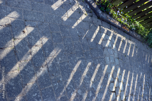 Holzzaum wirft einen Schatten auf das Strassenpflaster