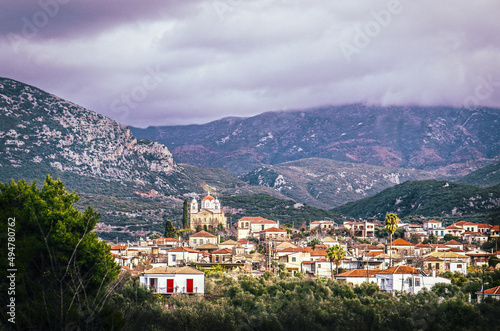 View down in valley at tile roofs of Greek village with large church in Taygetos Mountains between Kardamyli and Kalamata on Peloponnese Peninsula with foggy mountains in distance copy