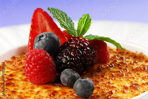 Creme brulee, caramel crust dessert with red berries, burnt cream close up view photo