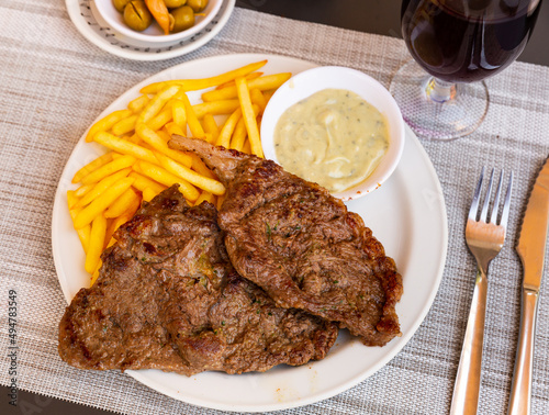 Beefseak with roquefort sauce and fried potatoes served on table in restaurant.