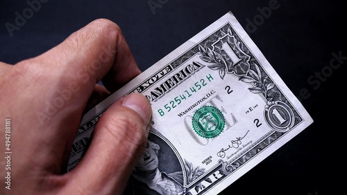 Businessman's hand holding American Dollar Banknotes, isolated on black background. Business Investment Economy Saving Loan Income Money and Finance concept. One Dollar, 1 USD. Prosperity concept.