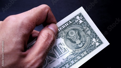 Businessman's hand holding American Dollar Banknotes, isolated on black background. Business Investment Economy Saving Loan Income Money and Finance concept. One Dollar, 1 USD. Prosperity concept.