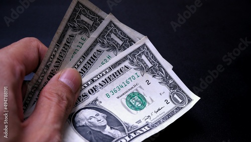 Businessman's hand holding American Dollar Banknotes, isolated on black background. Business Investment Economy Saving Loan Income Money and Finance concept. One Dollar, 1 USD. Prosperity concept.