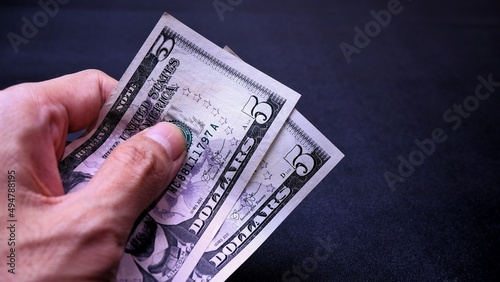 Businessman's hand holding American Dollar Banknotes, isolated on black background. Business Investment Economy Saving Loan Income Money and Finance concept. Five Dollar, 5 USD. Prosperity concept.
