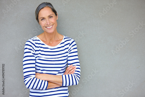 Confident beauty. Portrait of an attractive mature woman in casualwear standing against a gray wall.