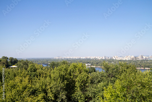 Panorama of Kyiv, in Ukraine, with a view over the Dnipro, or Dnieper river and the city center, in front of a green forest of trees, in Kiev, capital of Ukraine. ..