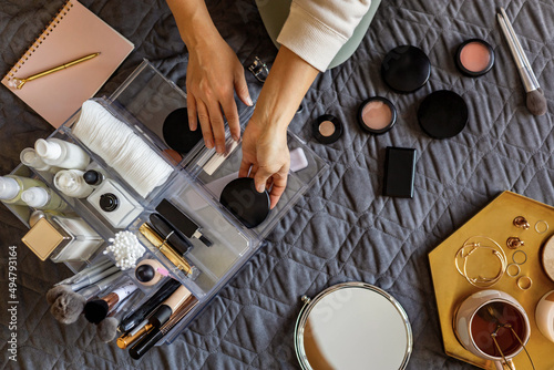 Woman hands tidying up putting powder container into acrylic storage box makeup products placement