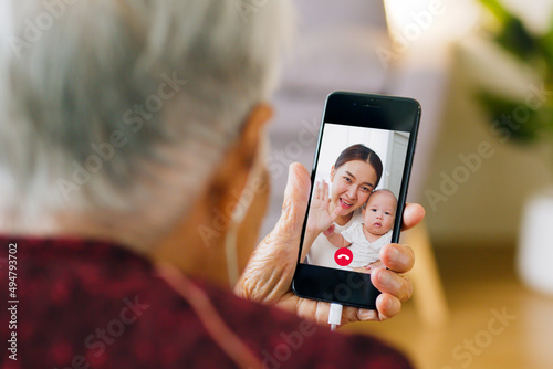 Asian old senior making video call via mobile phone talking with family