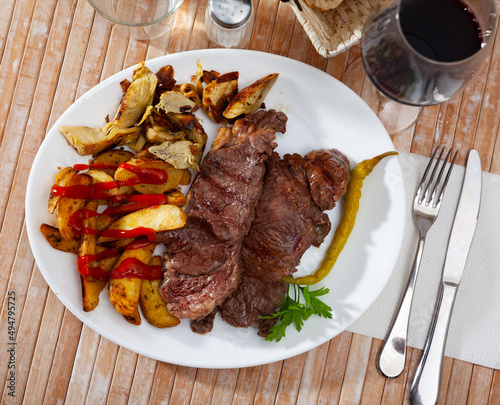 Appetizing beef steak with potatoes and artichokes