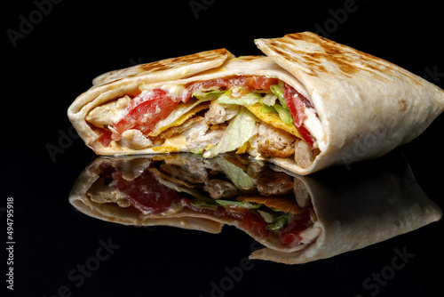 Juicy Mexican quesadilla with mozzarella, camembert and tomatoes. Isolated on black background.