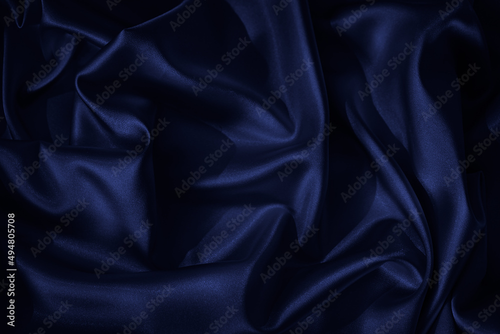 Fototapeta premium Navy blue silk satin. Beautiful wavy folds. Dark elegant background with space for design. The surface of the fabric.