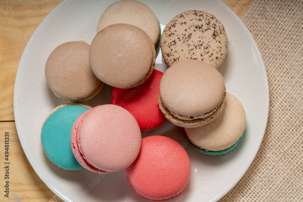 Close up macaron dessert pastel tones on white plate , Sweet and colorful french macaroons on wooden background, Dessert. Close up macaron dessert pastel tones on white plate , Sweet and colorful french macaroons on wooden background, Dessert.