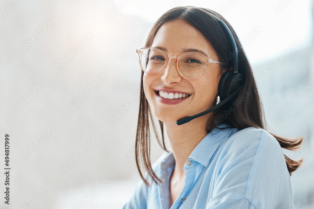 Leave the hard work to me. Shot of an attractive young saleswoman sitting alone in the office and wearing a headset. - obrazy, fototapety, plakaty 