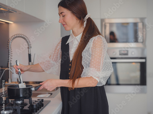 bakery, food and people concept. Beautiful woman cook chocolate cake with happy feeling in kitchen room. cooking chocolate meltng on stove photo