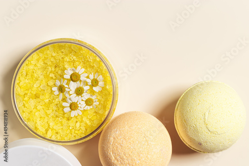 Top view bath bombs and sea salt with  herbal extract of chamomile, spa products close up. Natural cosmetic for beauty treatment and body care, home care, herbal medicine, beige background photo