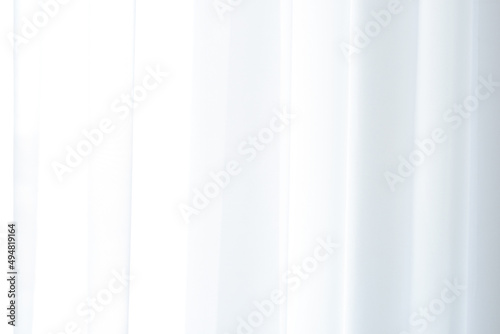 background texture of white transparent curtains on a window on a sunny day, white organza or chiffon curtains. Drapery of translucent white fabric