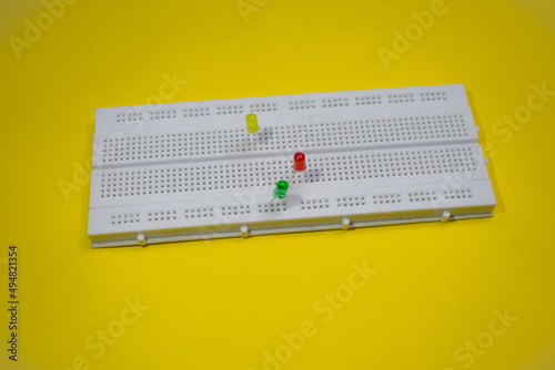 Electronic breadboard for college experiments with LED or light emitting diode isolated on a yellew background photo