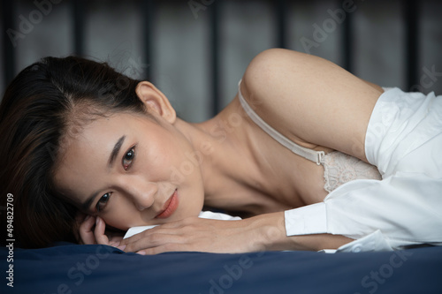 Happy young sexy Asian women lying on bed in bedroom at her house