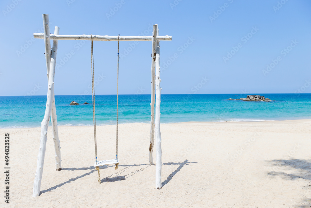 Fototapeta premium White wooden swing on tropical beach, relaxing by the beautiful blue sea in summer suny day, holiday destination beach in south of Thailand