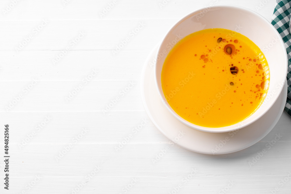 Pumpkin creamy soup served in bowl on white wooden background Pumpkin creamy soup served in bowl on white wooden background