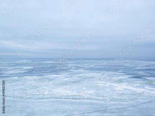 A frozen icy river and a cloudy sky in a single color connected on the horizon line. photo