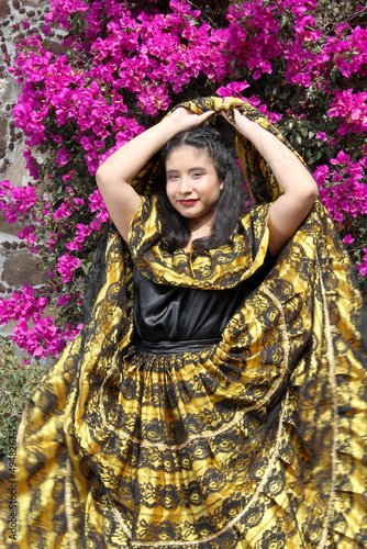 Young woman wears a traditional regional dress from the state of Chiapas, Mexico proud of the culture and tradition of her country with jacaranda flowers in the background 