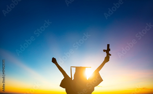 The silhouette of Student Celebrating Graduation watching the sunlight