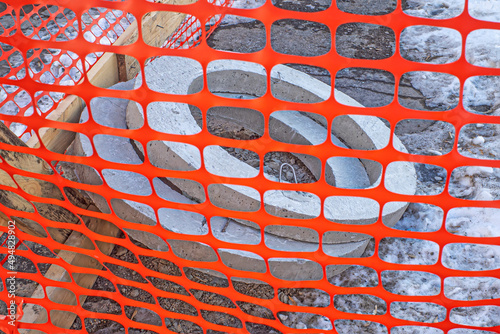 Concrete rings lie on the construction site behind a plastic fence