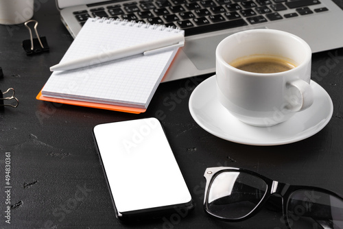 Notepad is on top of office desk table with laptop and supplies